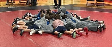 Local middle school wrestlers joined at center mat to give one last cheer of support for one another at the beginning of their home meet.